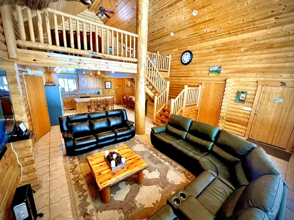 Spacious log cabin living room with vaulted ceilings and warm lighting