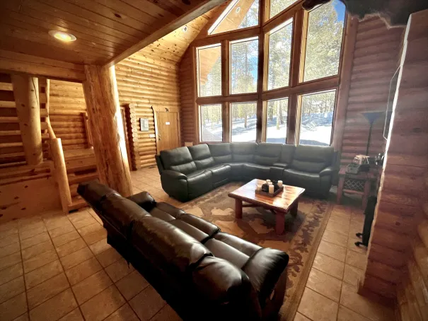 The front of the cabin features a large 2.5-story window offering scenic views with a sectional couch and 65-inch Smart TV