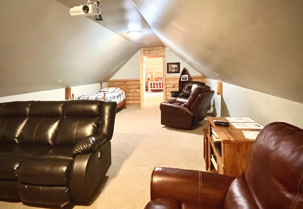 Comfy loft with plush couches, a cozy bed, and a projector screen for epic movie nights