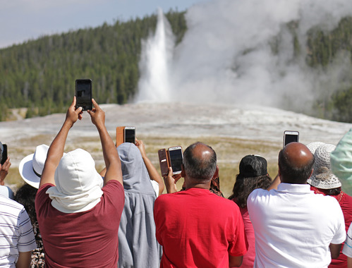 A photographer with a large-format camera capturing Old Faithful in Yellowstone